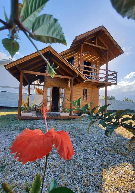 a house with a red flower in front of it at Cabana Rústica Praia do Sonho in Palhoça