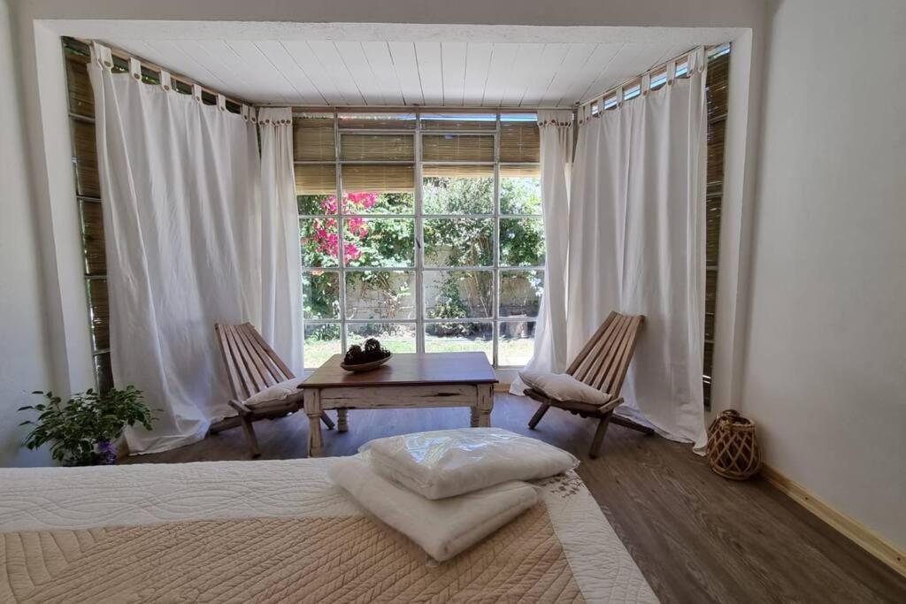 ein Schlafzimmer mit einem Tisch, Stühlen und einem Fenster in der Unterkunft Departamento de huéspedes con piscina y parrilla, Tranquilo y Céntrico in Colonia del Sacramento