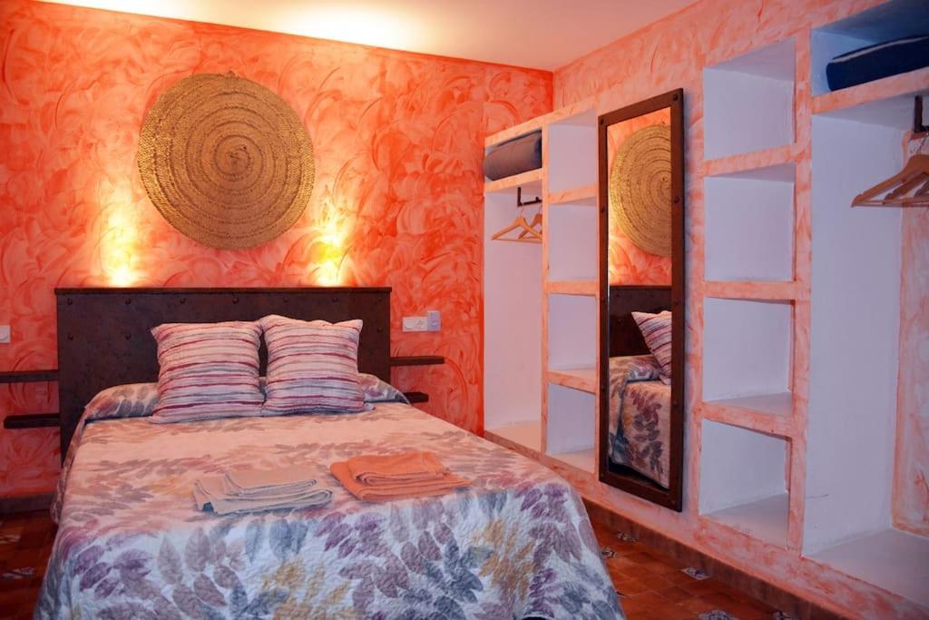 ルイデラにあるCasa Rural El Pajar de Pucheroのベッドルーム1室(オレンジ色の壁のベッド1台付)