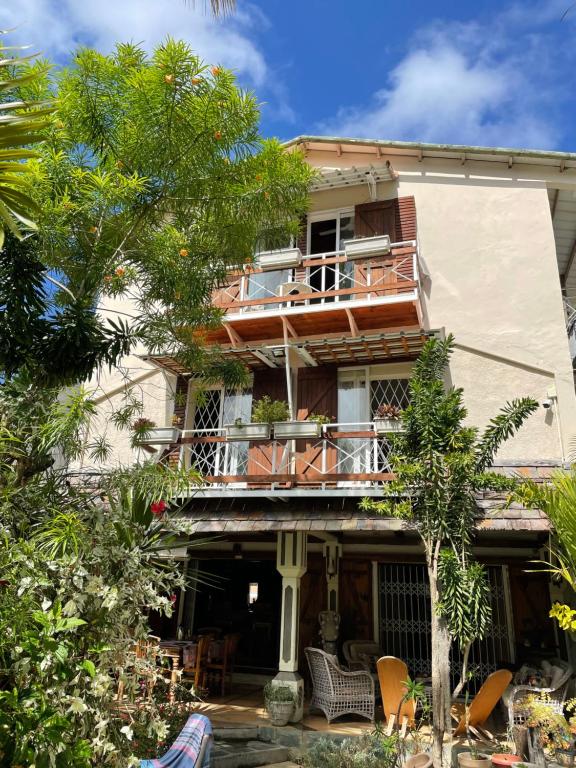 un edificio con balcón y árboles delante de él en Chez Henri, en Pointe d'Esny