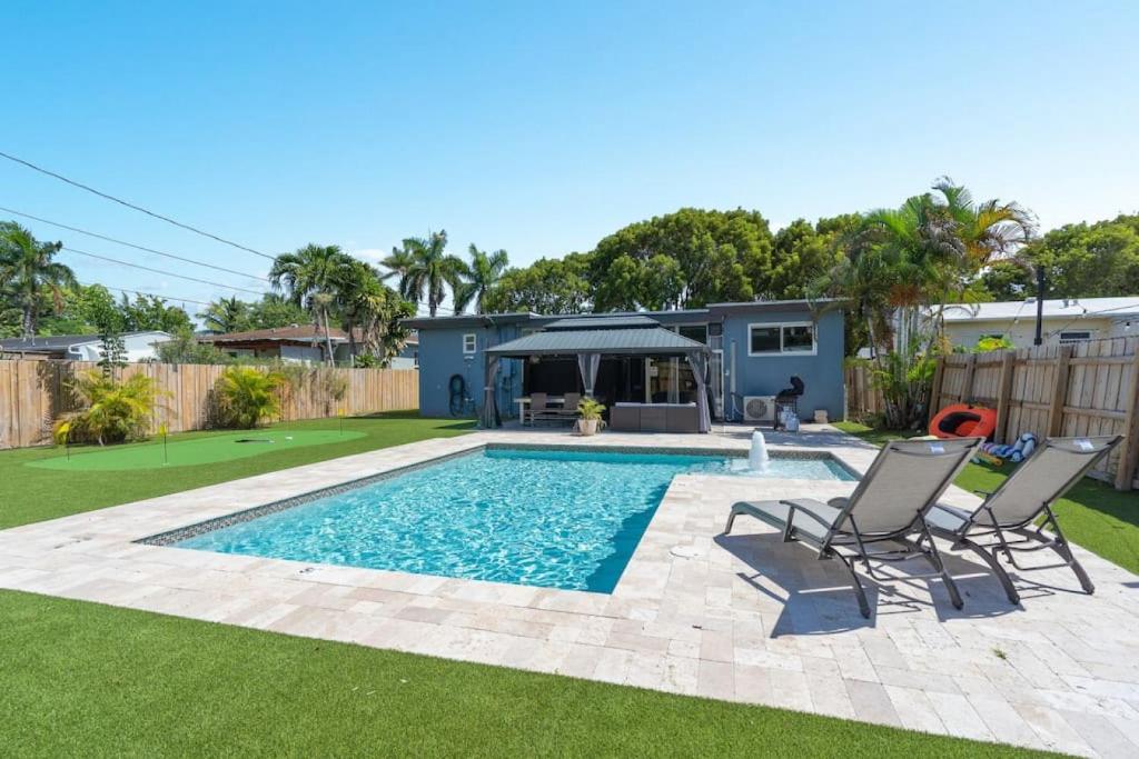 un patio trasero con piscina y 2 sillas en Wileys Paradise Three Bedroom Two Bath plus Office and Heated Pool, en Hollywood