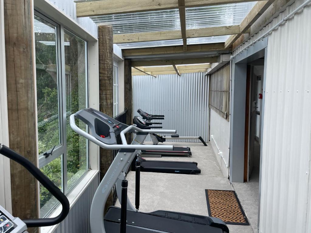 a row of exercise bikes in a gym with windows at Barbwire Bach in Opunake
