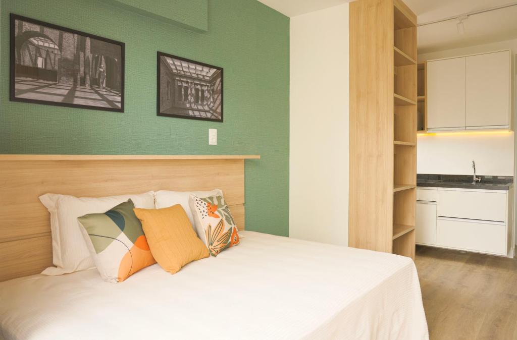 1 dormitorio con paredes verdes y 1 cama con almohadas en XBase Studio Parque Augusta-Higienópolis Mackenzie en São Paulo