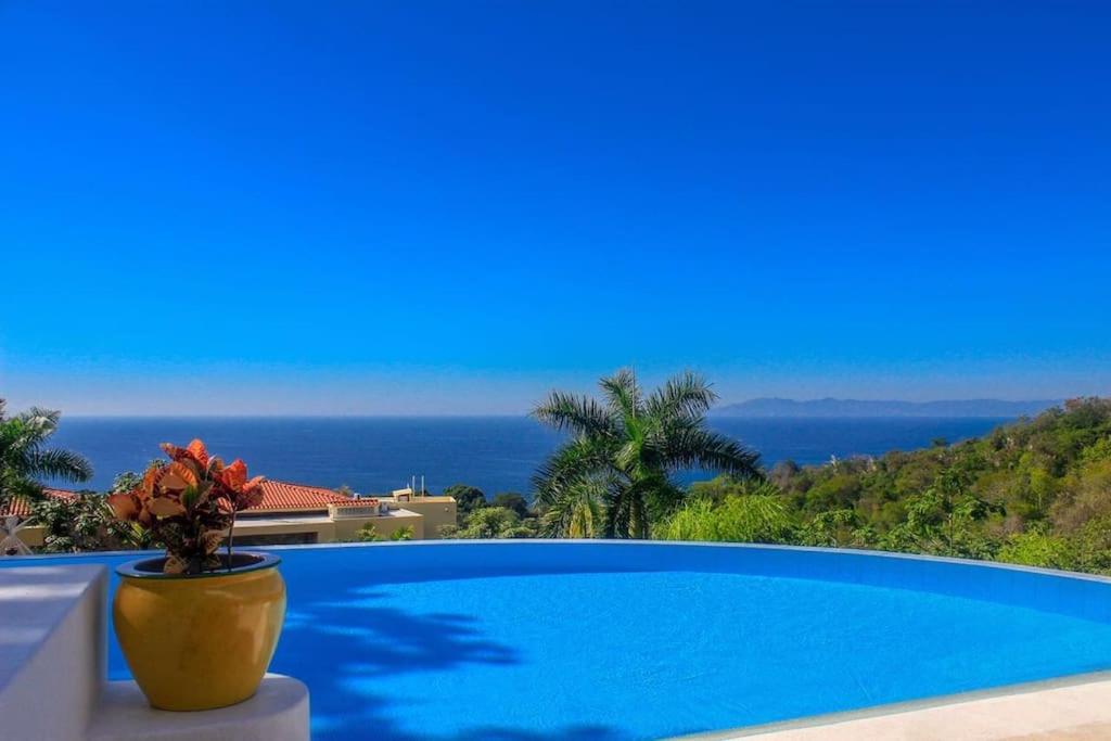 a blue swimming pool with a view of the ocean at Villa Mozzafiato Private Resort with Full Staff and Heated Pool in Puerto Vallarta