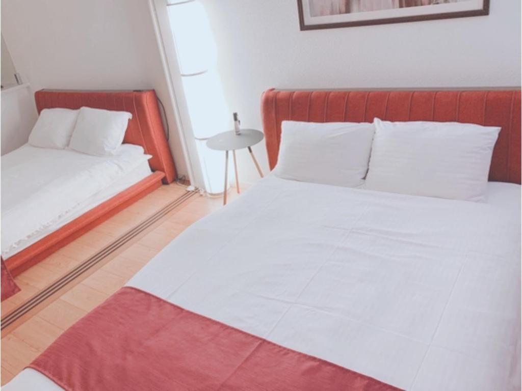 een slaapkamer met twee bedden met witte lakens en een rood hoofdeinde bij ＥＵＲＯＰＥＡＮ ＨＯＵＳＥ ＲＥＩＳＥＮ - Vacation STAY 10516v in Fukuoka