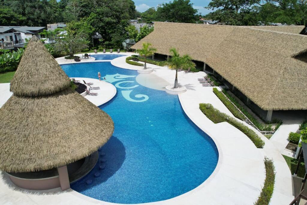 an overhead view of a resort swimming pool with straw umbrellas at Casa Cardumen - Ciudad Del Mar, in Jaco in Jacó