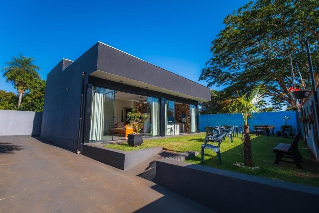 a modern house with a large glass window at Casa com 2 suítes, cozinha completa , área de lazer, piscina infantil, 10 min do parque aquático in Andradina