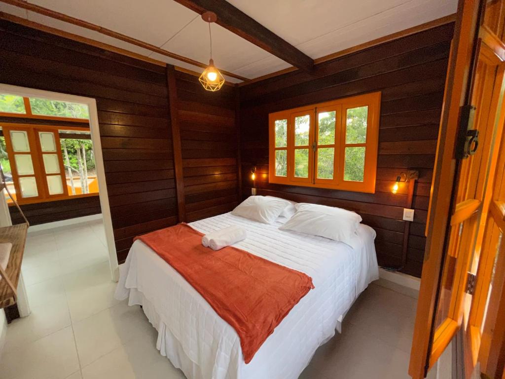 um quarto com uma cama com paredes e janelas de madeira em Chalés Mata da Praia Corumbau em Corumbau