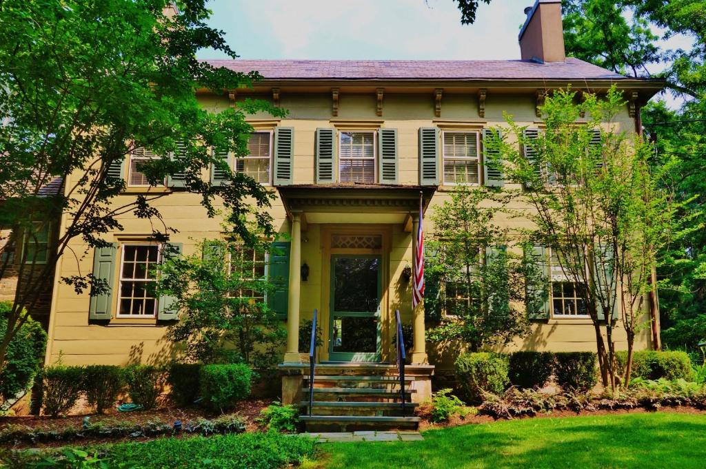 una vieja casa amarilla con una puerta principal en Inn at Glencairn en Princeton