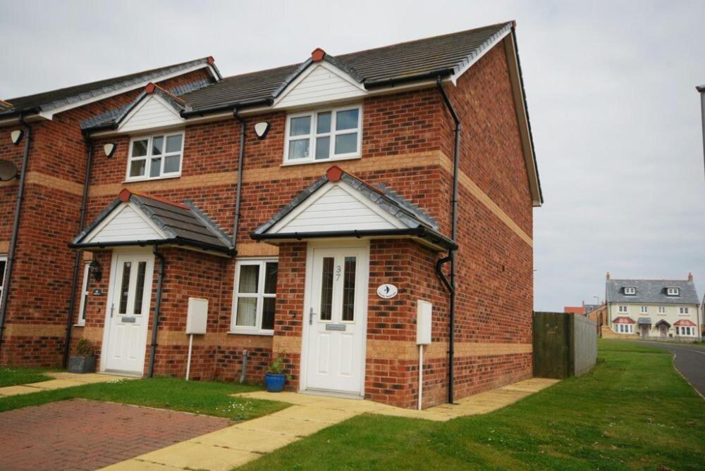a red brick house with two white doors at House Martins Beadnell in Beadnell