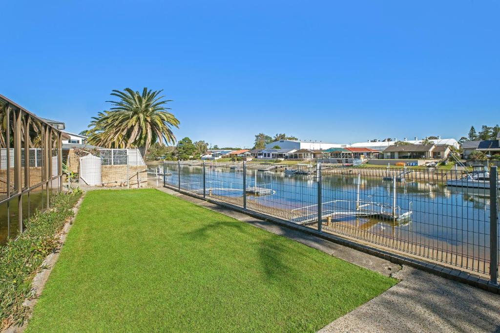 Ein Hof mit einem Zaun neben einem Wasserkörper in der Unterkunft 31 Cornwallis Close in Port Macquarie