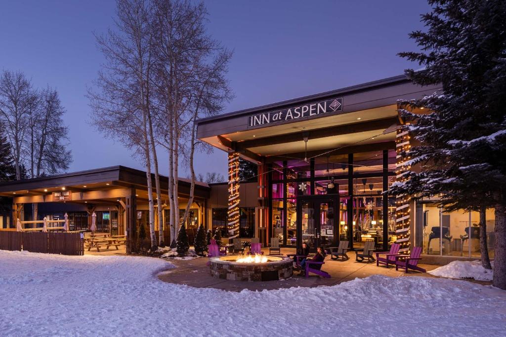 un bâtiment avec une table en face de lui dans la neige dans l'établissement The Inn at Aspen, à Aspen