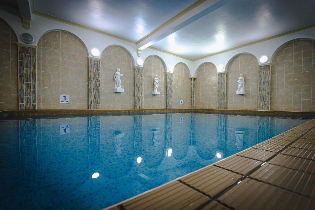 a swimming pool with statues in a building at Chatsworth House Hotel in Llandudno