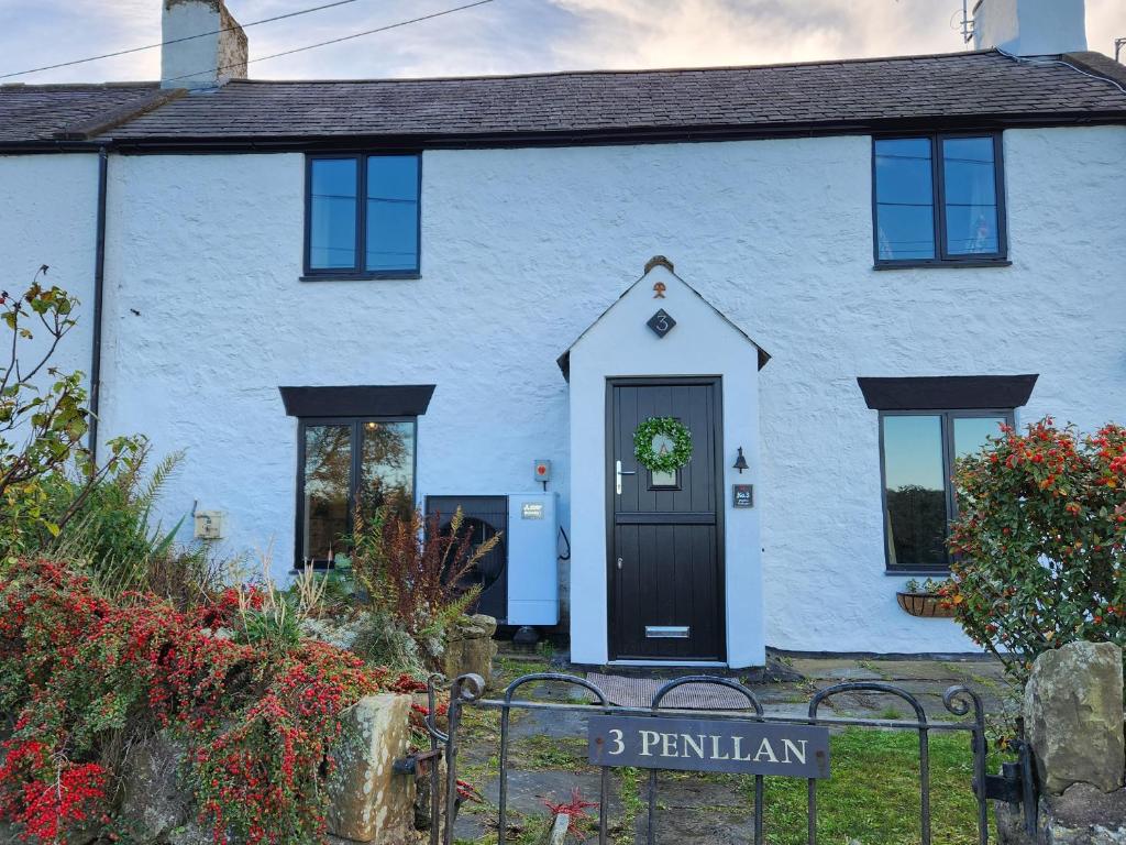 a white house with a black door at 3 Penllan Cottages in Holywell