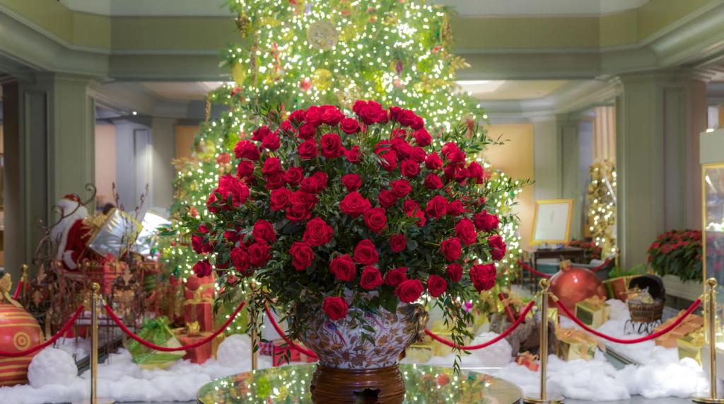 um vaso cheio de rosas vermelhas em frente a uma árvore de Natal em The Windsor Court em Nova Orleães