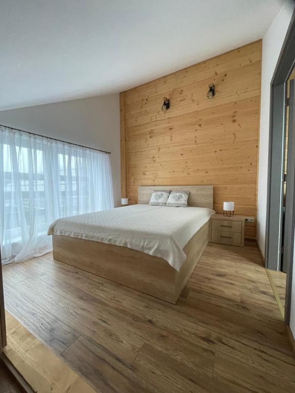 a bedroom with a large bed and a wooden wall at U plechového Jánošíka in Terchová