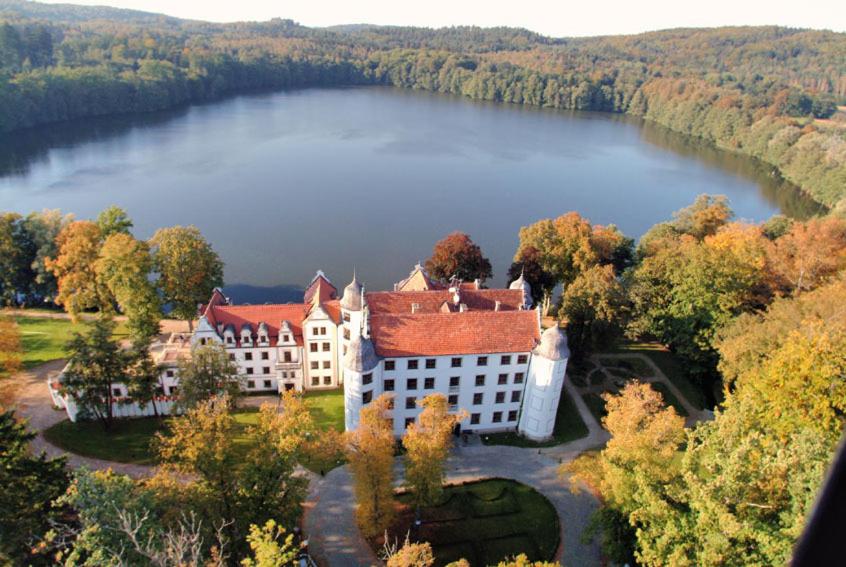 an aerial view of a large building on a lake at Zamek Podewils Krag in Krąg