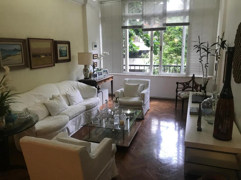 sala de estar con muebles blancos y mesa de cristal en Ipanema 3 quartos lindos, en Río de Janeiro