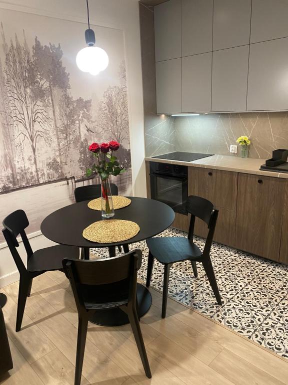 a kitchen with a table and chairs and a table with roses at Apartamenty Sonata, Mazury, Szczytno in Szczytno