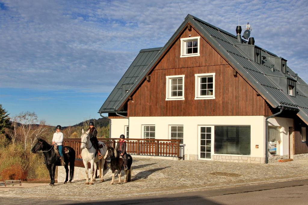 a group of people riding horses in front of a barn at Farma Severák in Janov nad Nisou