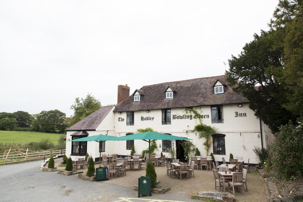 a white building with tables and chairs in front of it at Hadley Bowling Green Inn in Droitwich