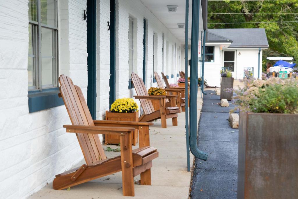 Al & Sally's Motel في ميتشيغان سيتي: صف من الكراسي الخشبية تجلس خارج المبنى