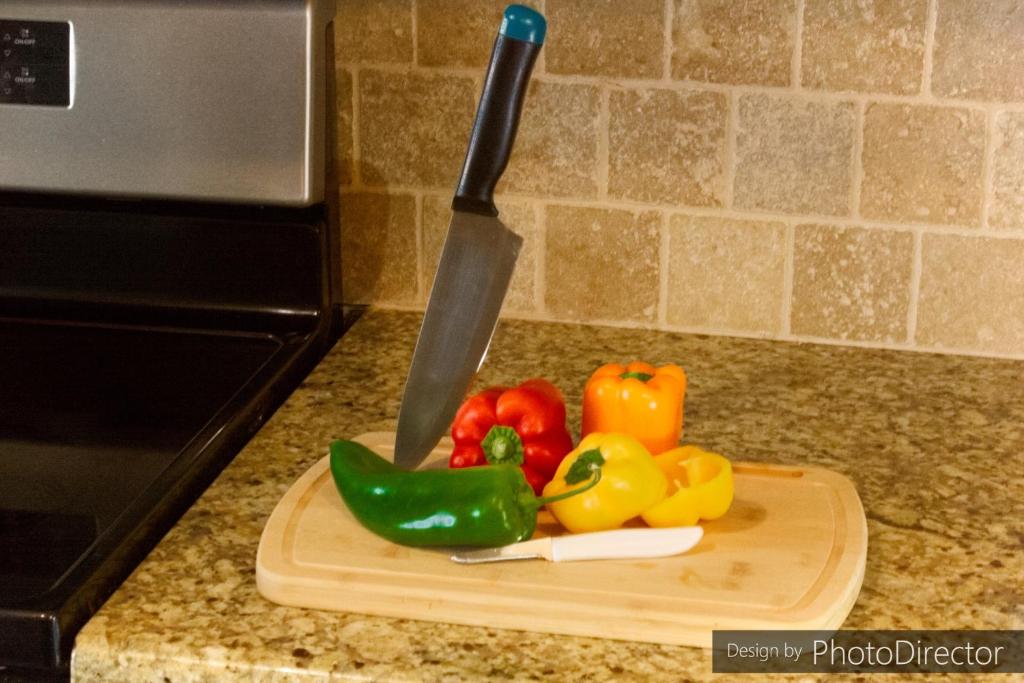 a knife and vegetables on a cutting board on a counter at Amazin All-inclusive Apartment! A in College Station