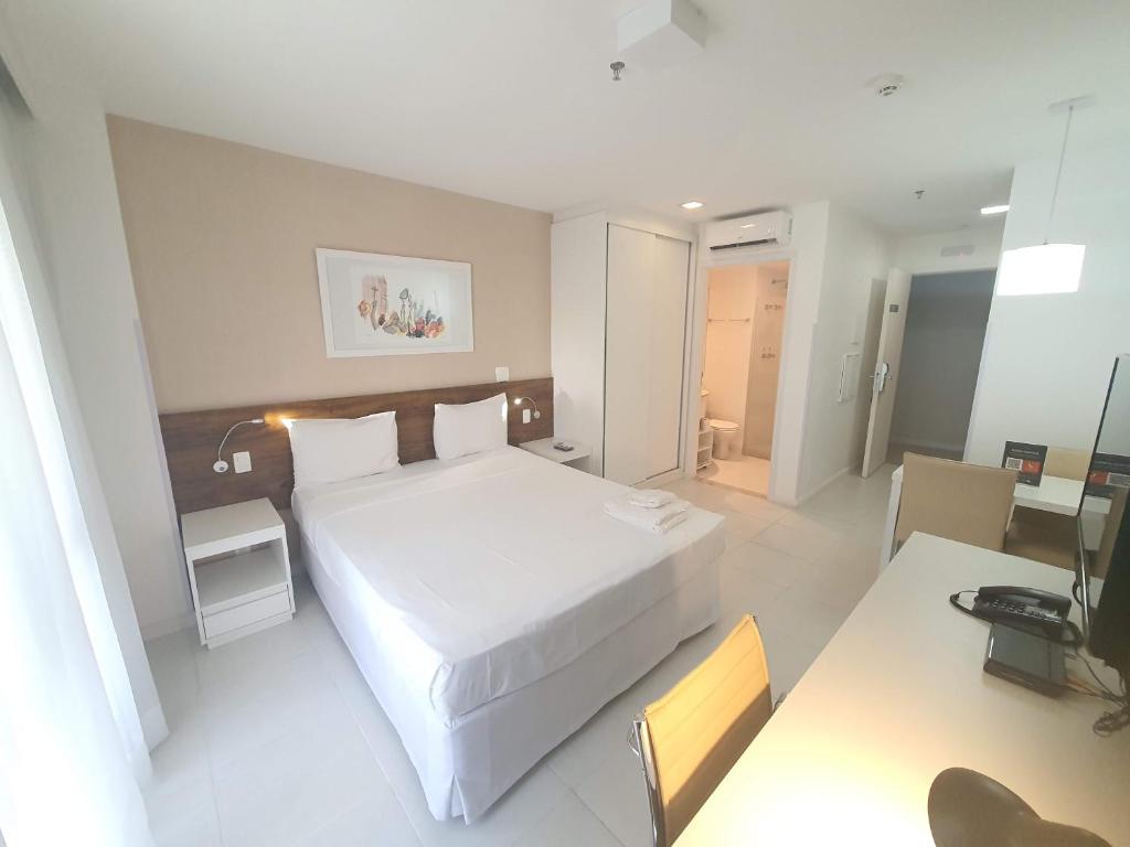 1 dormitorio con 1 cama blanca grande y escritorio en Vision Executive Express III, en Brasilia