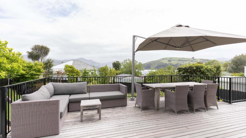 une terrasse avec un canapé, une table et un parasol dans l'établissement Spacious Sunny Family Home in Akaroa, à Akaroa