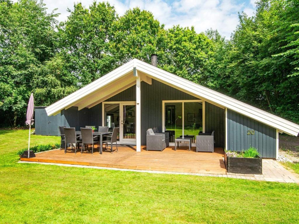 a pavilion with a deck and chairs in a yard at Holiday home Oksbøl LXXVIII in Oksbøl