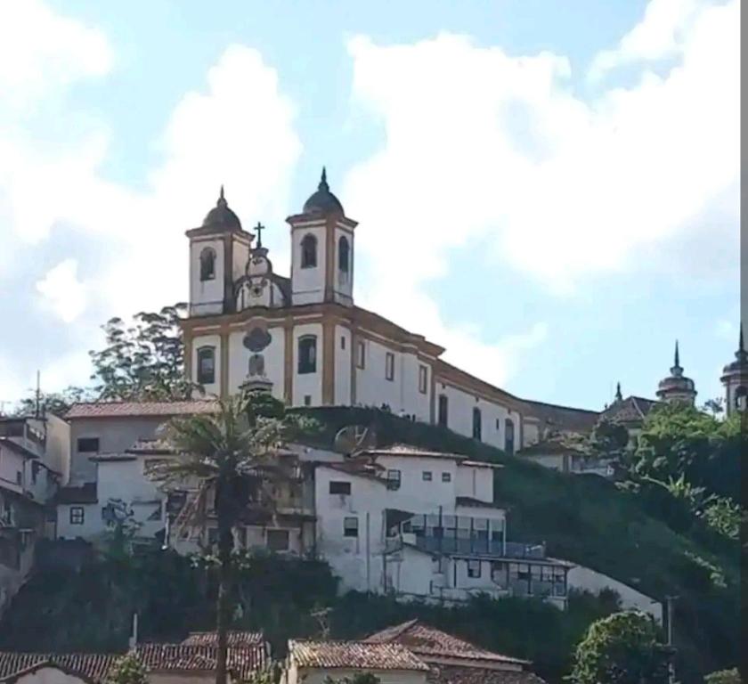 kościół na szczycie wzgórza z domami w obiekcie Estúdio ( Kitnet ) confortável w mieście Ouro Preto