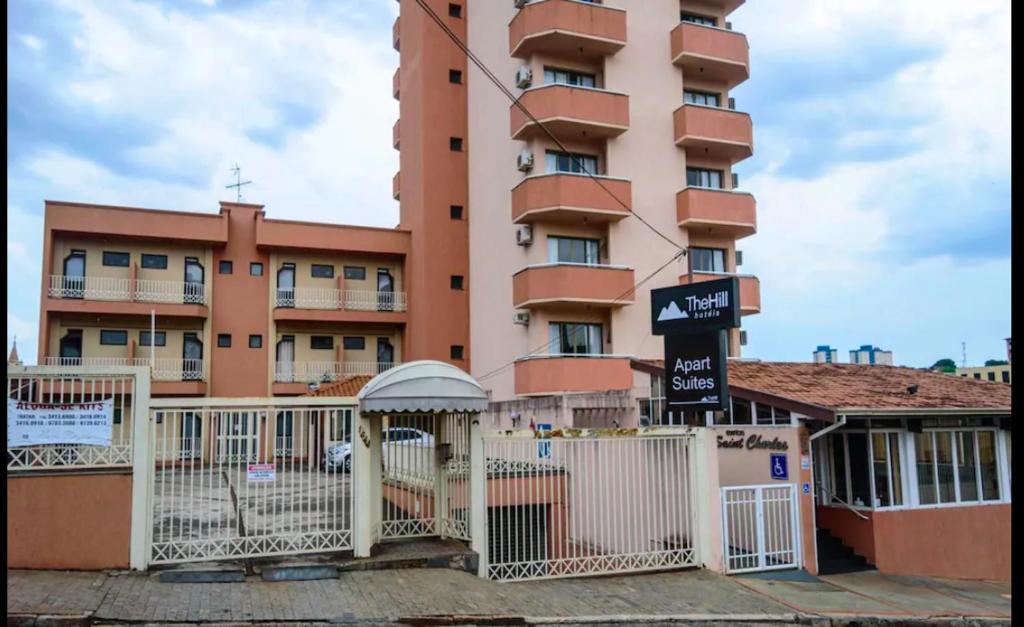 un gran edificio rosa con una valla blanca delante de él en Bravo Suites São Carlos, en São Carlos