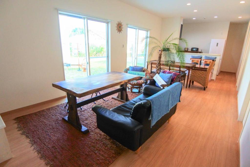 een woonkamer met een tafel en een bank bij 2019新築 ! guest house Holoholo beach side in Ishigaki Island