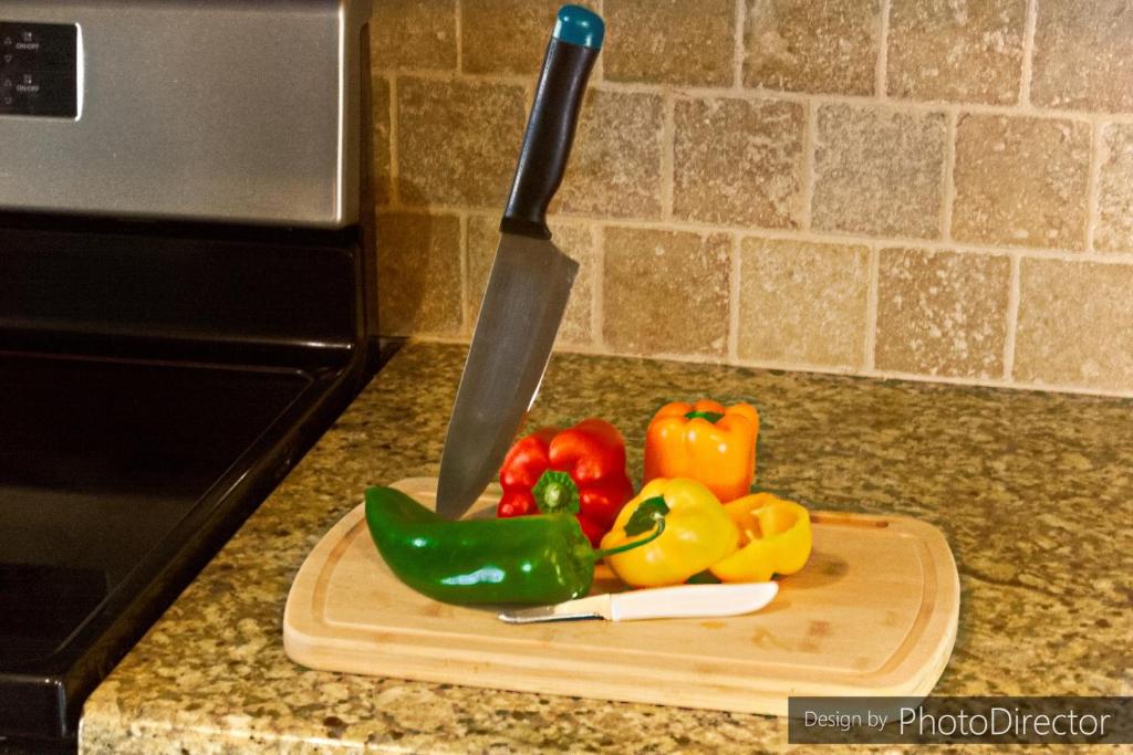 a knife on a cutting board with vegetables on a counter at Cool & Comfy Condo! Family Friendly! in College Station