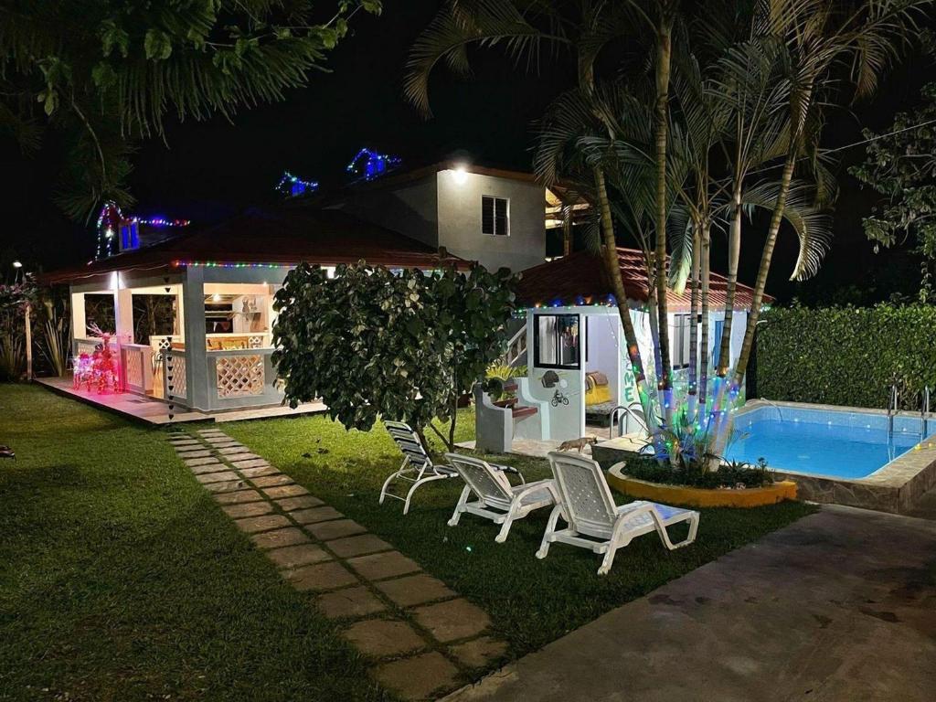 una casa con sillas y una piscina por la noche en Villa Los Caciques By Hospedify - Hermosa Villa con Piscina, Billar, Zona de BBQ y Domino, en Jarabacoa