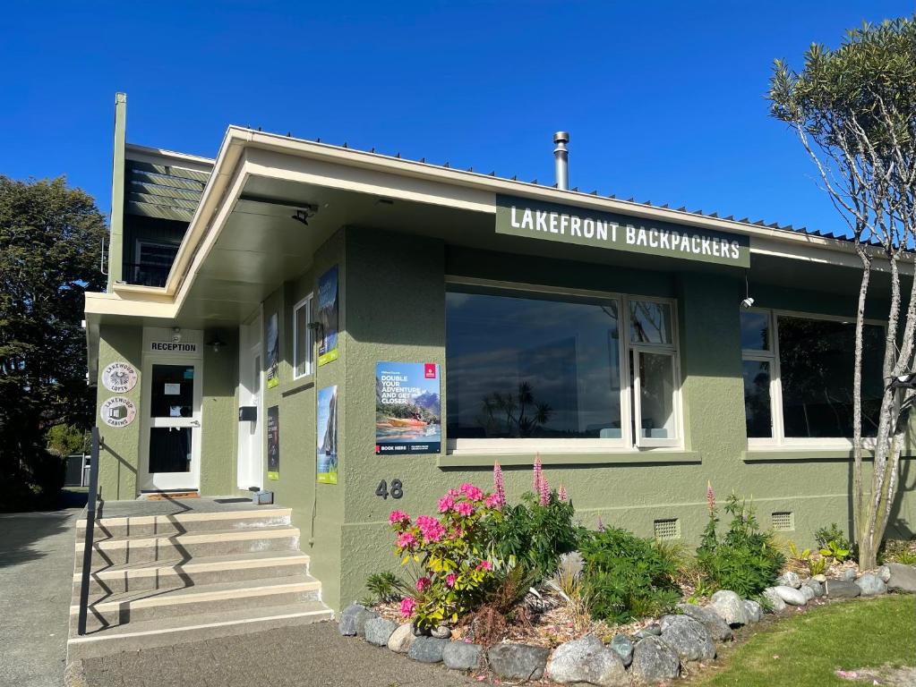 a green library building with flowers in front of it at Te Anau Lakefront Backpackers in Te Anau