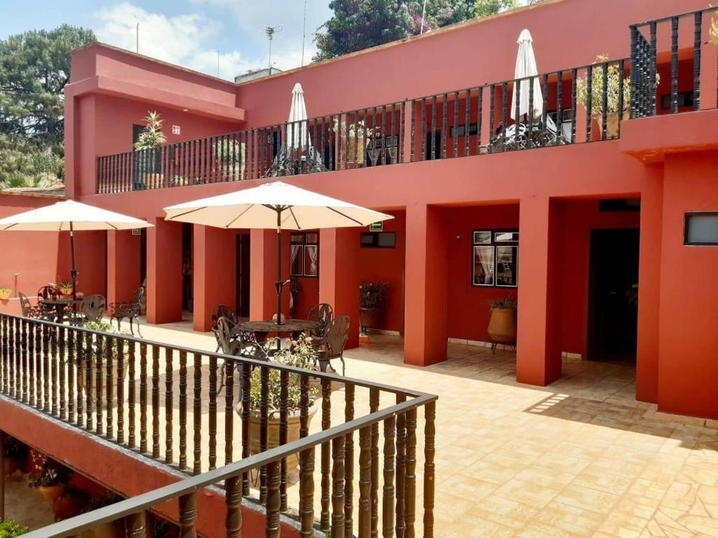 een roze gebouw met tafels en parasols ervoor bij posada San Alejandro in Pátzcuaro