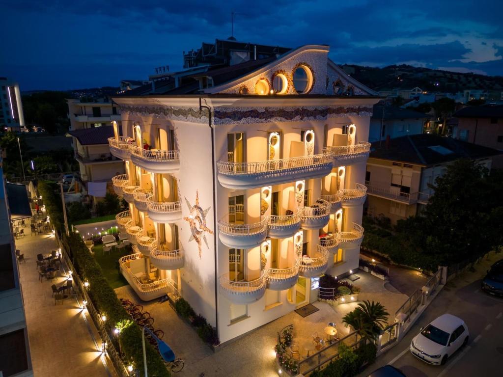 Un grand bâtiment blanc avec des lumières allumées la nuit dans l'établissement Residence Anchisemare, à Alba Adriatica