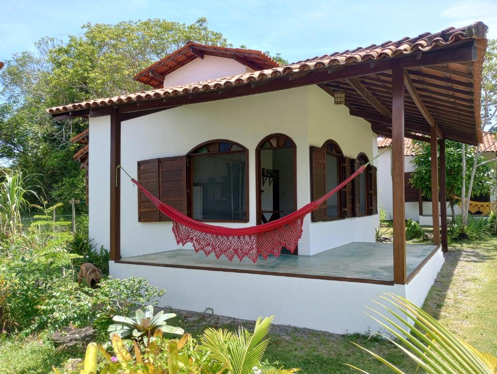une petite maison avec un hamac rouge en face de celle-ci dans l'établissement Cores do Mar Cabanas, Taipu de Fora, à Barra Grande