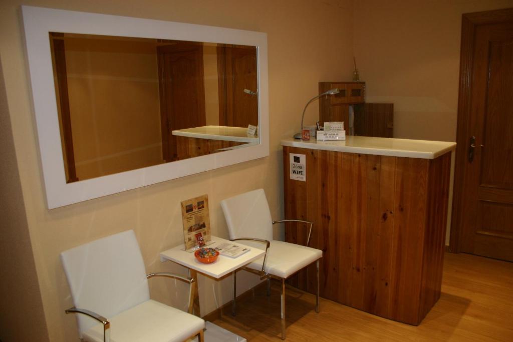 サラマンカにあるHostal Hispanico Iの椅子2脚、テーブル1台、鏡1台が備わる客室です。