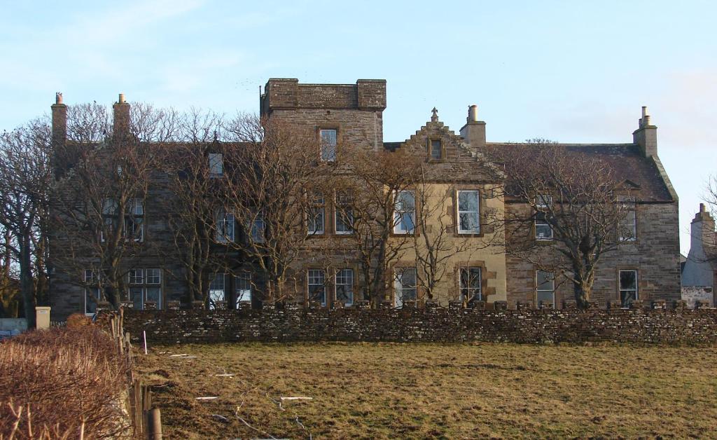 an old house with a stone fence in front of it at Highland Park House in Kirkwall