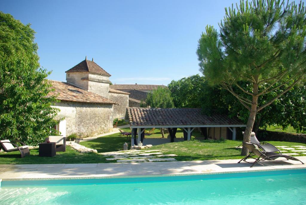 a man sitting on a chair next to a swimming pool at Domaine de Bel Air Carpe Diem in Tizac-de-Curton