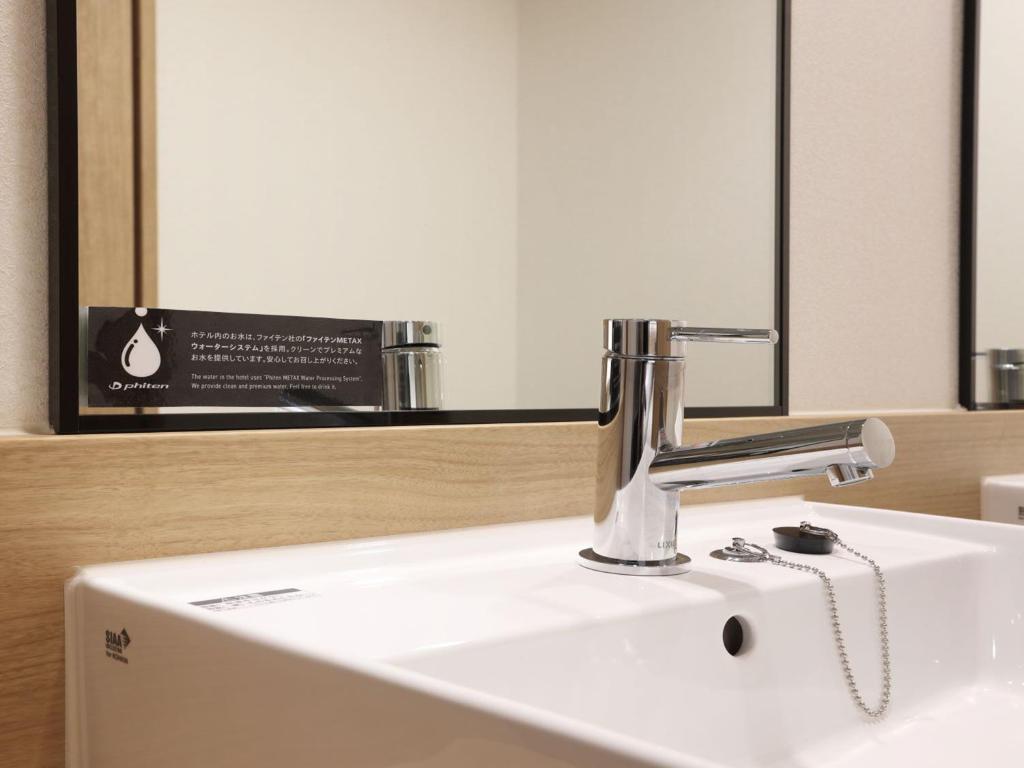a bathroom sink with a faucet next to a mirror at Henn na Hotel Premier Nagoya Fushimiekimae in Nagoya