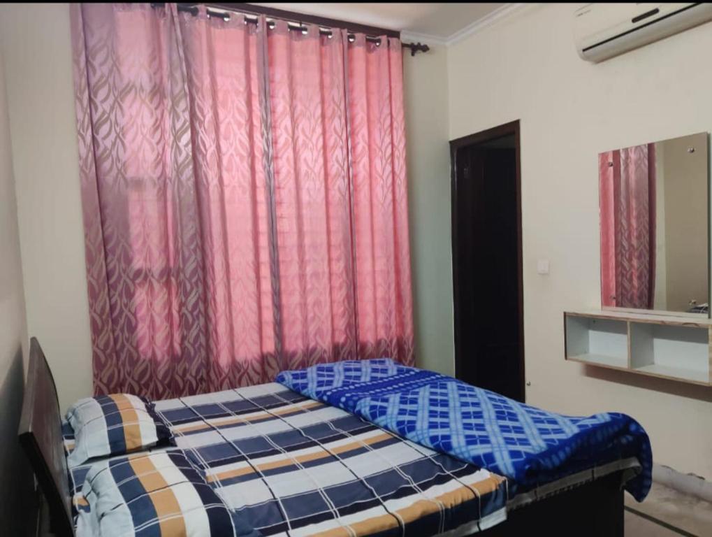 uma cama num quarto com cortinas vermelhas em Angad home fully furnished Ac wifi included ground floor em Kharar