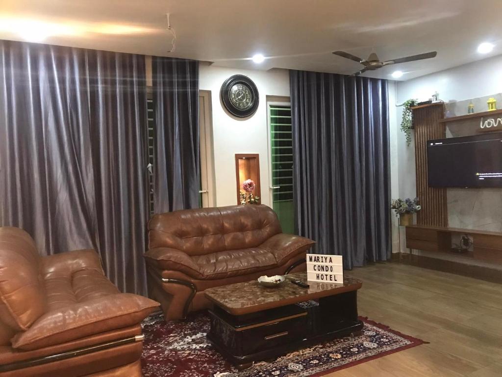 a living room with a leather couch and a tv at Mariya Condo hotel in Bodh Gaya