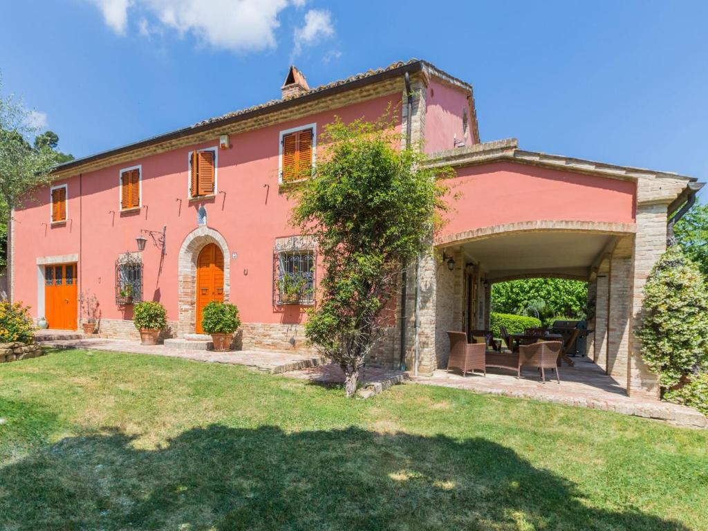 a large pink house with a yard at Belvilla by OYO Villa Azzurra in Mondavio