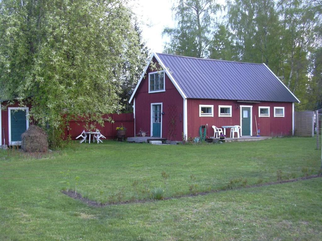 una casa roja con una mesa de picnic delante de ella en Ringbomsvägen Holiday Home en Ljugarn