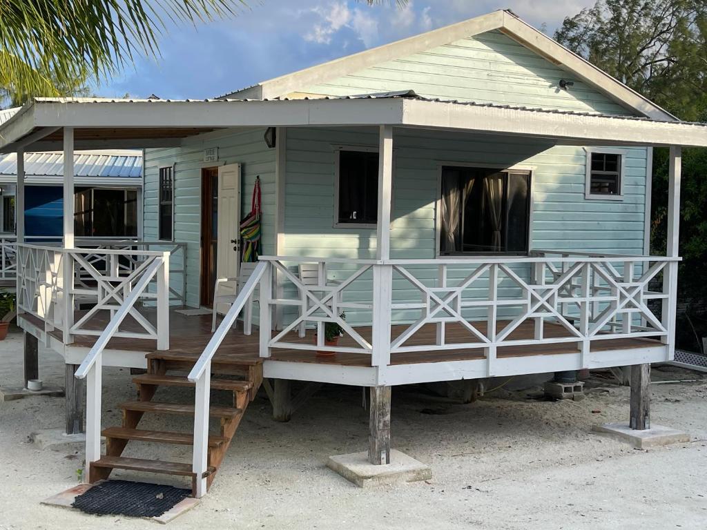 a small blue house with a porch and stairs at Hidden Treasure Vacation Home Blue Bay Cottage in Caye Caulker