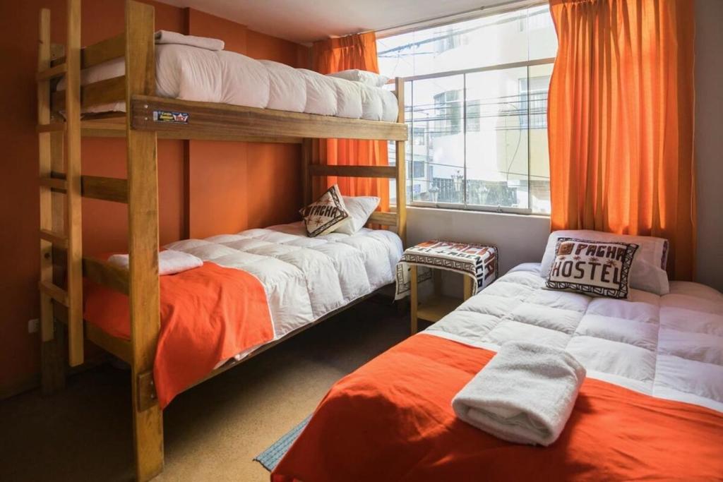 sypialnia z 2 łóżkami piętrowymi i oknem w obiekcie Pacha Hostel w mieście Puno