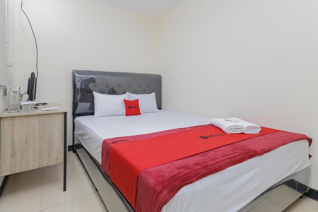 a bedroom with a bed with a red blanket on it at RedDoorz near RS Sari Asih Ciledug in Jakarta